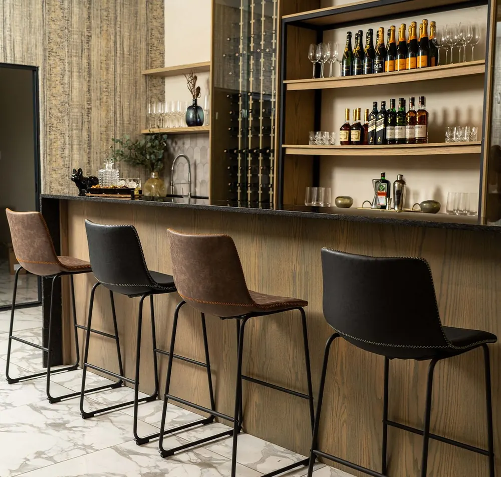 Bar counter with tall stools and a wall of bottles