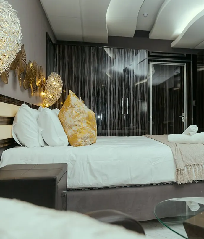 King bed with gold cushions and a sculpted ceiling light in a Deluxe King Suite