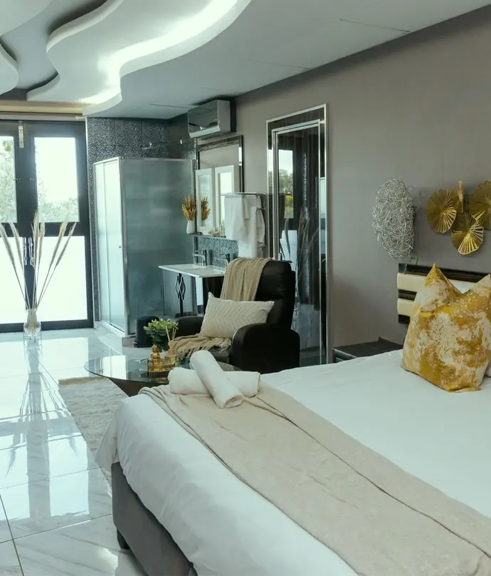 Bed, seating and gold wall décor in a Deluxe King Suite