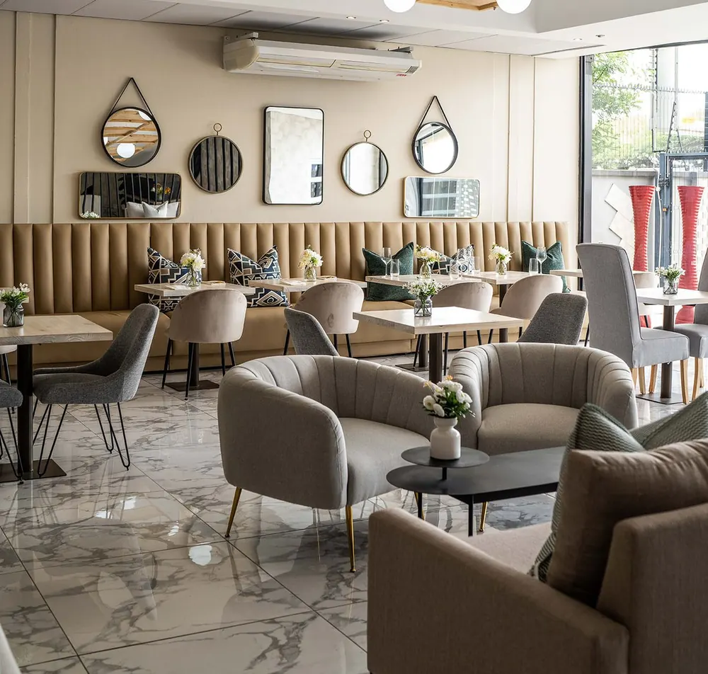 Restaurant dining area with armchairs, banquette seating and mirrors