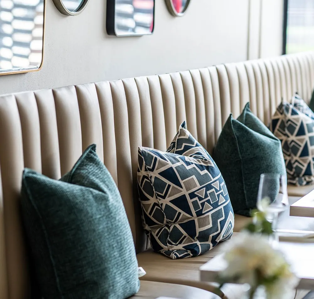 Banquette seating with teal and patterned cushions and fresh flowers